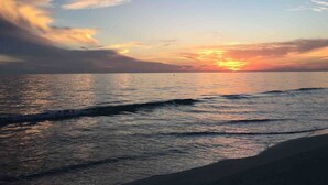 A sunset over a calm sea with waves gently lapping onto the shore.