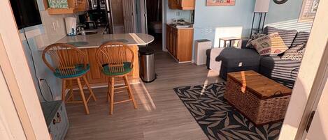 Un espacio habitable compacto con kitchenette, comedor y un dormitorio con sofá y cama.