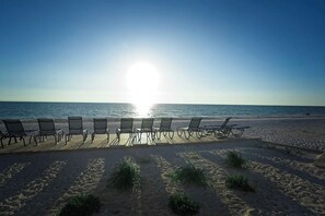 Ein Strand mit Liegestühlen, die auf einem Holzdeck in Richtung Meer ausgerichtet sind.