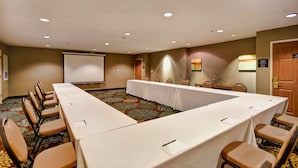 A conference room with a long table, chairs, a projector screen, and a carpeted floor. - Free Breakfast Pool & Hot Tub. Near East Towne Mall! (Madison)