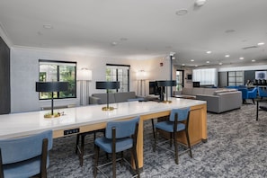 A modern hotel room with a long dining table, multiple chairs, a sofa, and a TV. - Free Breakfast Pool & Hot Tub. Near East Towne Mall! (Madison)