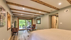 Een slaapkamer met een groot bed, houten balken in het plafond, een bureau met stoel, en uitzicht op de omgeving.