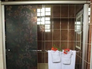 Bathroom features a floral-patterned wall, a towel rack with two white towels, and a small vase with fresh flowers.