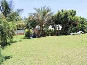 Relax in a serene, shaded environment surrounded by lush trees and a manicured lawn.