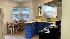 Una cocina compacta con comedor, estufa y ventana con persianas.