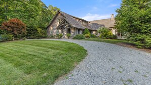 Une maison en pierre avec une allée en gravier et une pelouse bien entretenue.