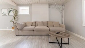 Una sala de estar moderna con un sofá seccional color beige, una mesa de centro de madera y una planta en maceta.