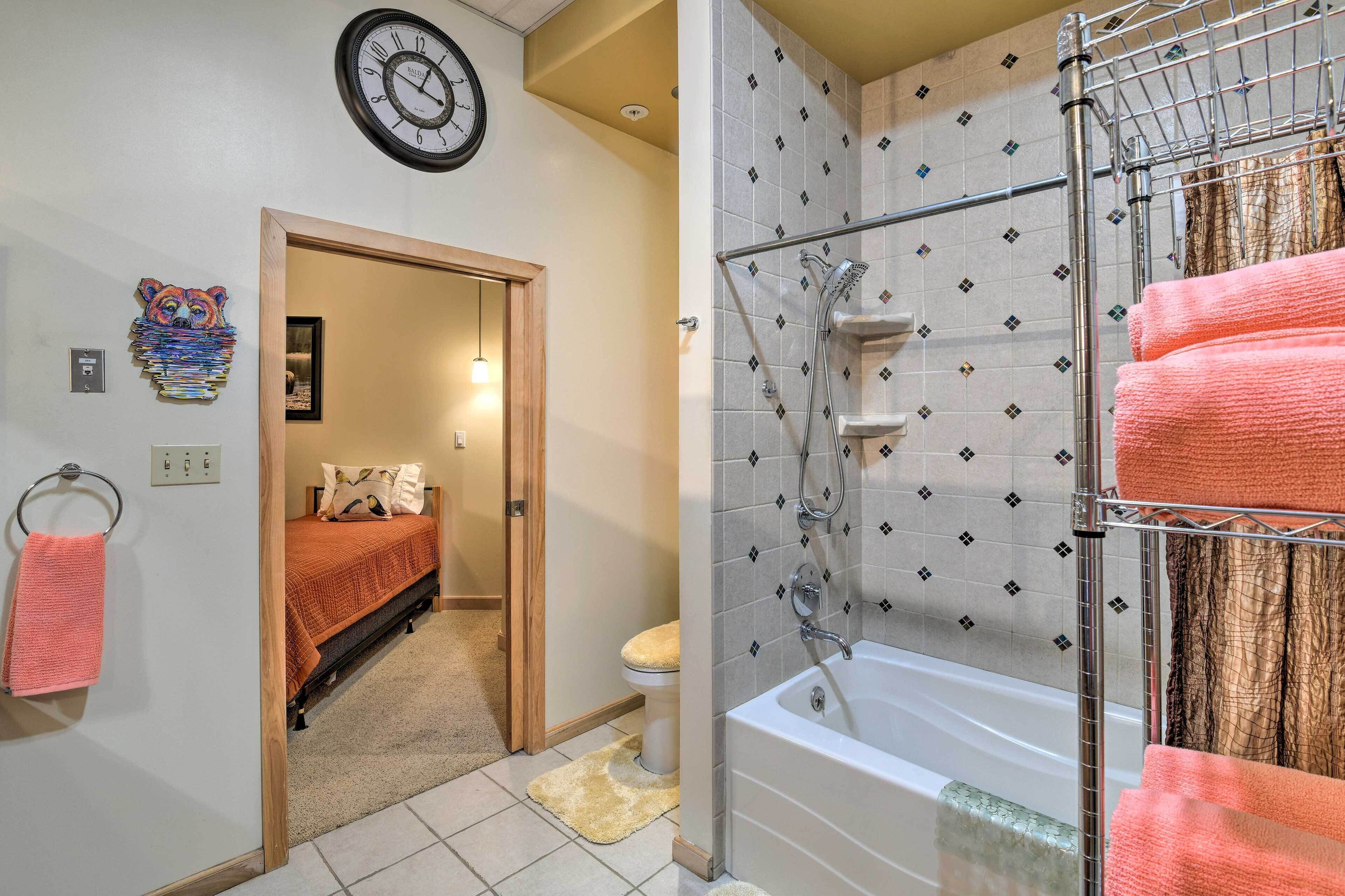 A bathroom with a bathtub, shower, and a towel rack with towels.