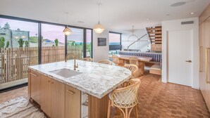 Una cocina moderna con una isla de mármol, armarios de madera y sillas de mimbre.