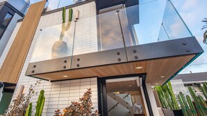Un edificio moderno con fachada de vidrio, listones de madera y una gran estructura tipo sombrilla.
