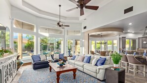 A spacious living room with a large sofa, two armchairs, a coffee table, and a dining area with a kitchen in the background. - 4BR w pool, heated spa, fire pit (Mesa)
