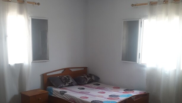 A bedroom with a bed, nightstand, chair, and a patterned rug.