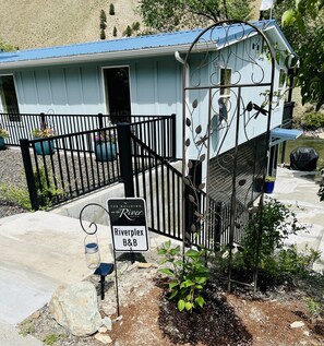 A small, light blue building with a metal fence and a sign reading "Riverplex B&B".