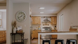 Una cocina moderna con armarios de madera, un refrigerador de acero inoxidable y una isla central con taburetes.