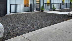 Un motel moderno con techo plano, un área exterior cubierta y vista a una colina verde al fondo.