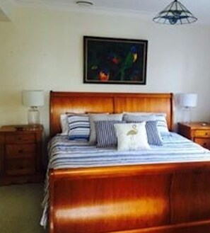 Cozy bedroom with a large bed, nightstands, and a painting above the headboard.