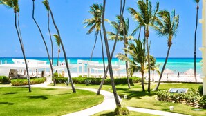 A resort with a pathway leading to a beach, surrounded by palm trees and a clear blue sky. - Playa Turquesa I-202 Premier Beachfront Ocean View 85 mbps wifi (Punta Cana)
