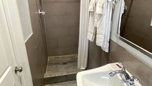 A bathroom with a shower, a sink, and a mirror.