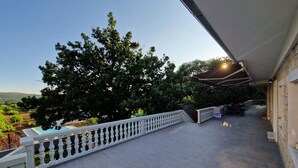 A covered outdoor area with a tiled floor, a white balustrade, and a view of trees and hills. - NEW Holiday Apartment,A4+2, Family house - OPG Rudan, garden pool, terase, wi-fi (Radonić)