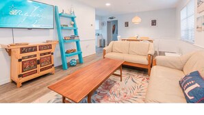 Un salon chaleureux avec un meuble en bois, une étagère bleue, un canapé beige et une table basse en bois.