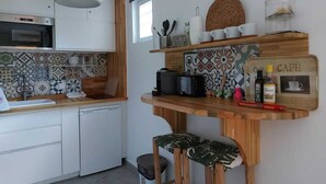 Una cocina compacta con horno empotrado, espacio para café y una pequeña zona de estar con taburetes.