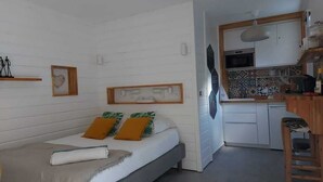 Una habitación compacta con cama, una pequeña kitchenette y zona de comedor.