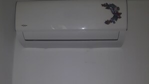 Eine weiße Klimaanlage an der Wand montiert, mit Bedienfeld darunter.