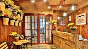 A wooden interior with a reception desk, chairs, and a patterned floor. - Awuka Guesthouse (Hangzhou)
