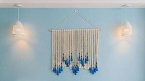 A room with a blue wall, a white headboard, and a hanging macrame piece with tassels. - Awuka Guesthouse (Hangzhou)
