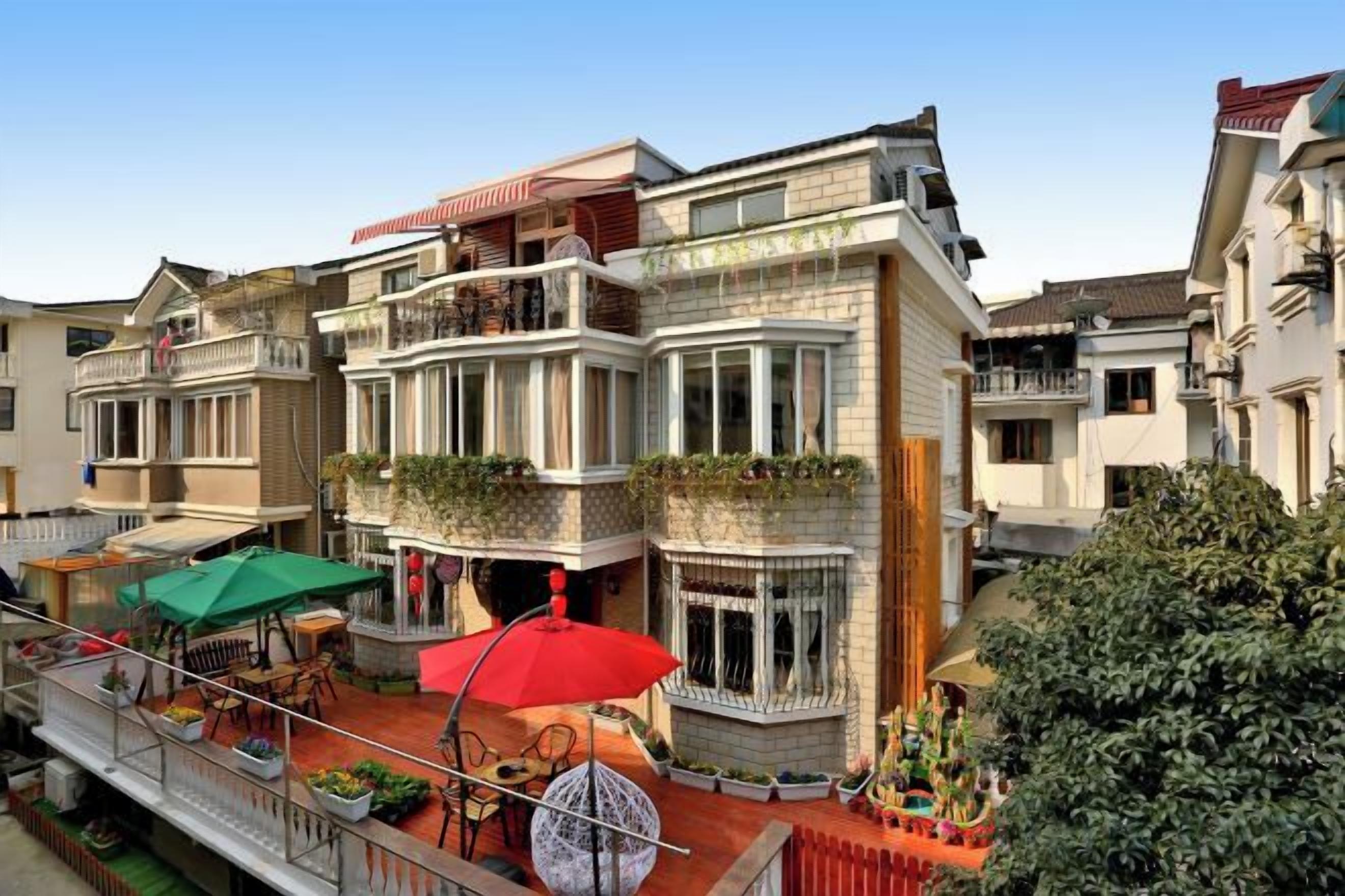 A multi-story building with balconies, outdoor seating, and a garden area.