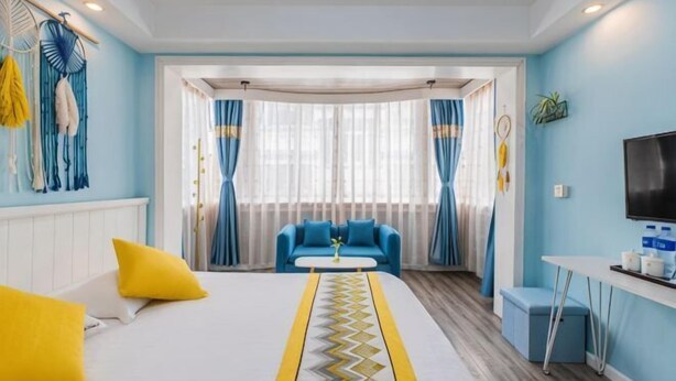 A hotel room with a bed, a sofa, a TV, and a window with curtains. - Awuka Guesthouse (Hangzhou)