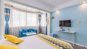 A hotel room with a bed, a blue sofa, a TV, and a desk.