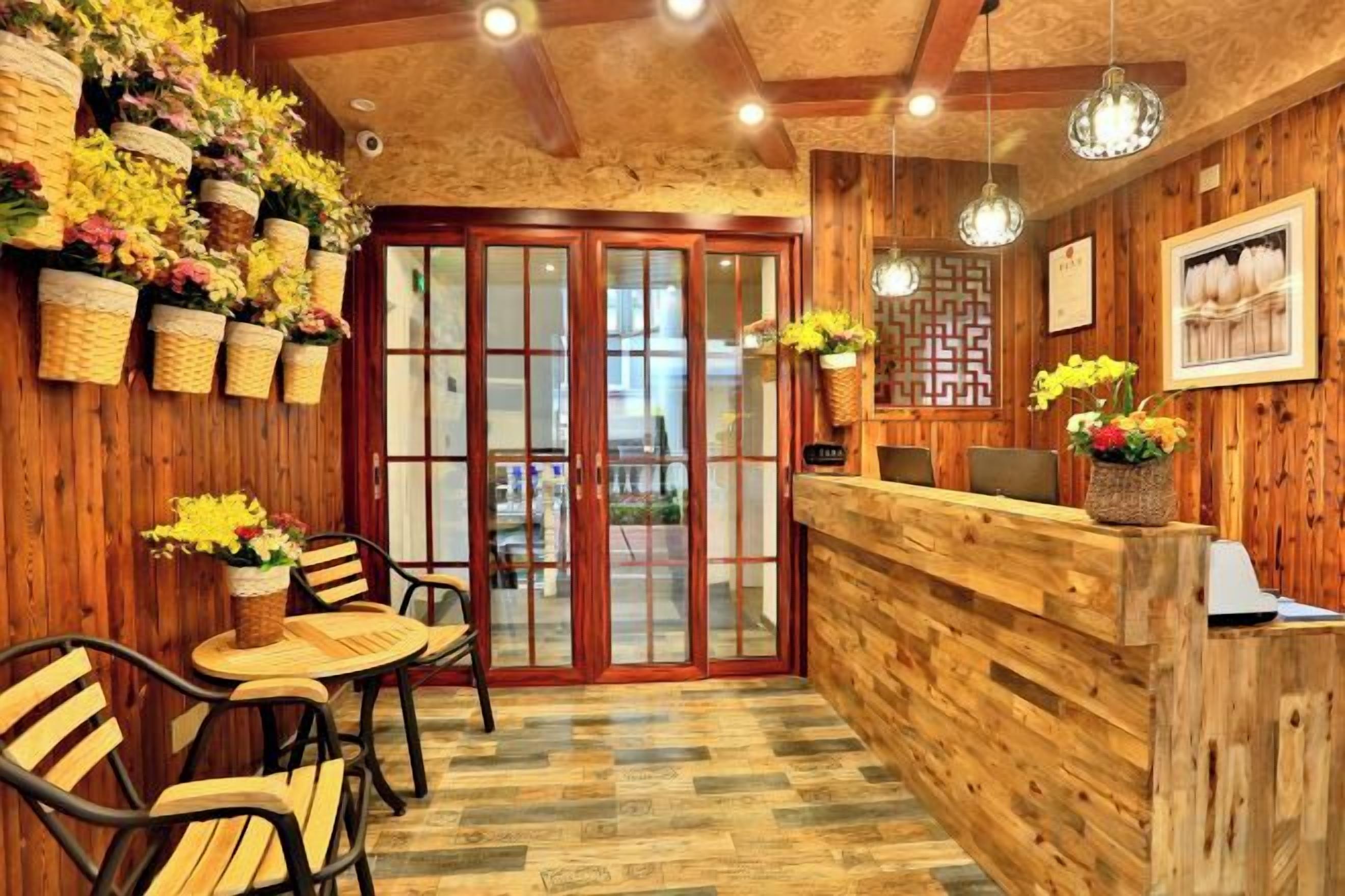 A wooden interior with a reception desk, chairs, and potted plants.