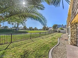 Surrounded by a lush lawn and a palm tree, this serene setting offers a tranquil escape.