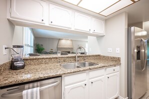 Enjoy cooking in this well-lit kitchen with a refrigerator, dishwasher, and sink.