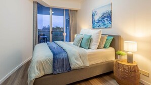 A modern bedroom with a large bed, a view of the outdoors, and a painting on the wall.
