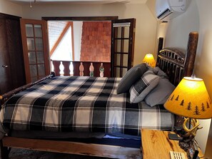 Une chambre à coucher avec un lit, une tête de lit en bois, une table de chevet avec une lampe et un radiateur fixé au mur.