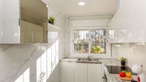 A modern kitchen with white cabinets, a marble countertop, a window with a view, and a sink. - Stunning private villa for 6 people with WIFI, private pool, A/C, TV, terrace and pets allowed (Maçanet De La Selva)