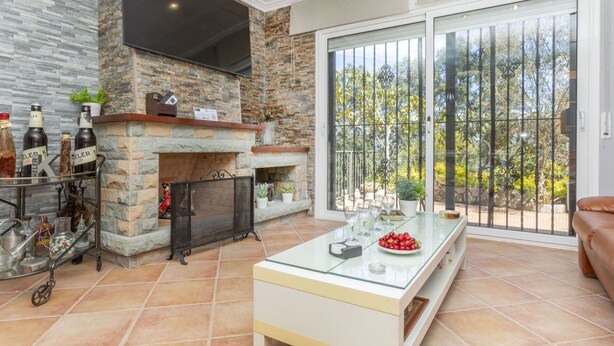 A modern living room with a stone fireplace, a glass coffee table, and a sliding glass door leading to a balcony. - Stunning private villa for 6 people with WIFI, private pool, A/C, TV, terrace and pets allowed (Maçanet De La Selva)