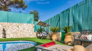 A backyard with a swimming pool, artificial grass, a stone wall, a hammock, and potted plants. - Stunning private villa for 6 people with WIFI, private pool, A/C, TV, terrace and pets allowed (Maçanet De La Selva)