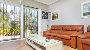 A living room with a glass coffee table, a brown leather sofa, and a sliding glass door leading to a balcony with a view of greenery. - Stunning private villa for 6 people with WIFI, private pool, A/C, TV, terrace and pets allowed (Maçanet De La Selva)