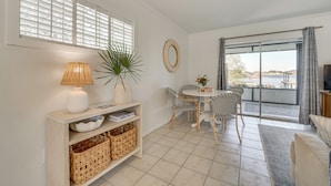 A modern living room with a dining area, large windows with blinds, a TV, and a view of the outdoors. - Lakefront Retreat w/ Kayaks & Fire Pit in Clermont (Clermont)