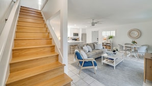 A modern interior with a wooden staircase, a living area with a sofa, coffee table, and chairs, and a kitchen in the background. - Lakefront Retreat w/ Kayaks & Fire Pit in Clermont (Clermont)