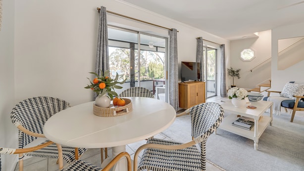 A modern living room with a round white table, patterned chairs, a television, and a view through large windows. - Lakefront Retreat w/ Kayaks & Fire Pit in Clermont (Clermont)
