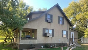 A two-story house with a covered porch, a satellite dish, and a fenced yard. - Entire house for fishing, hunting, or passing by! (Fairfax)