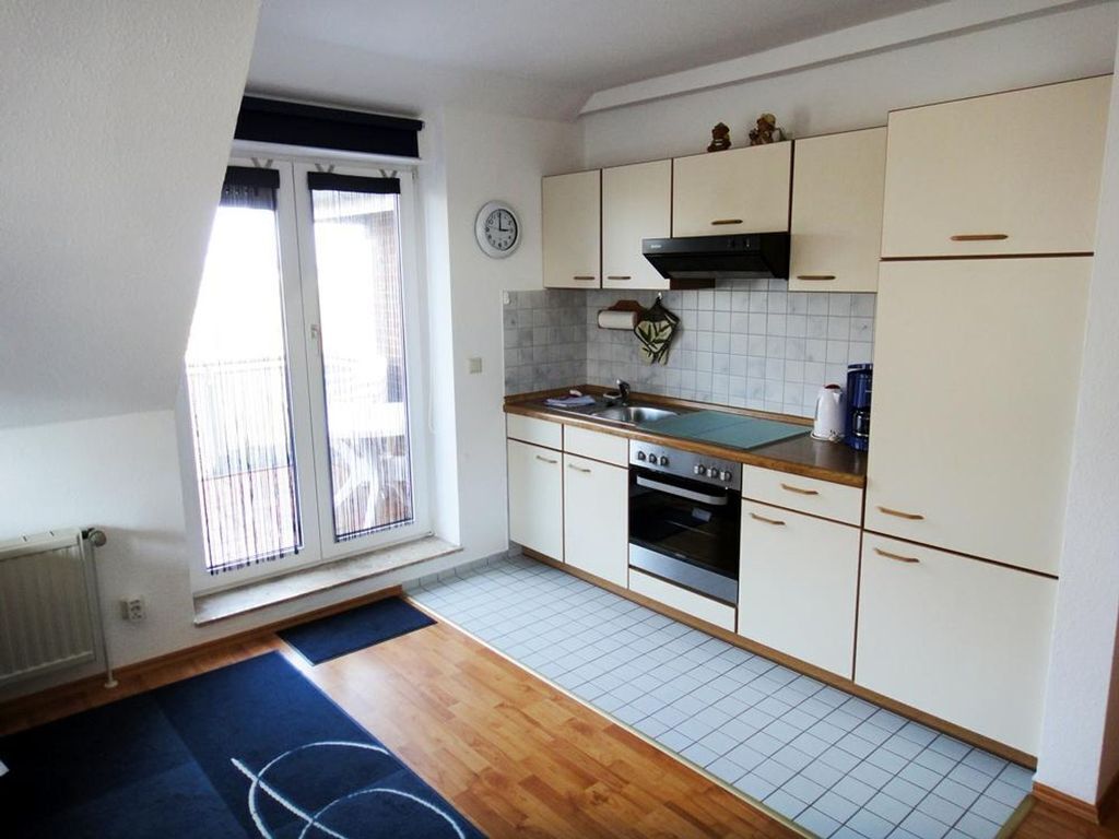 A kitchen with white cabinets, a stove, oven, and a window with blinds.