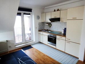 Una cocina con armarios blancos, estufa, horno y una ventana con persianas.