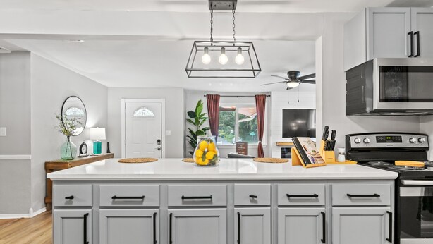 Una cocina moderna con armarios blancos, una isla central, un microondas y una estufa.