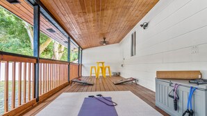 Una terraza de madera con un tapete de yoga, taburetes amarillos y equipo de ejercicio.