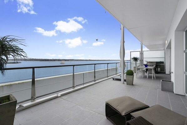 A balcony with a view of the sea, a dining area, and a lounge with seating.